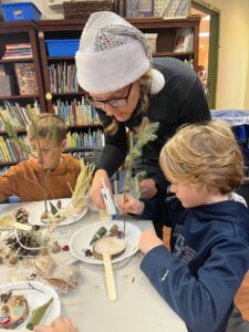 Photo of a volunteer helping a student make a gnome garden during Winter Faire