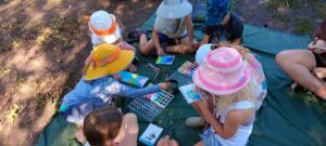 Forest school students use watercolor paints while outside in the woods